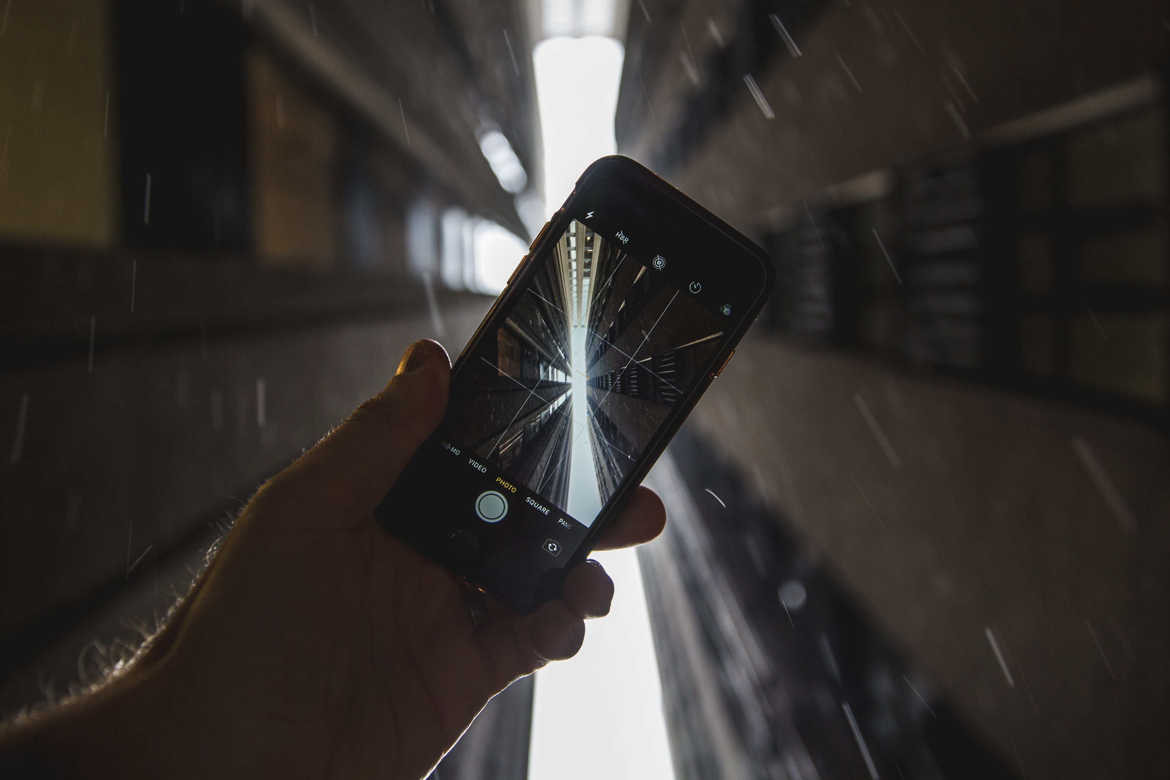 Hand holding a phone camera towards the sky